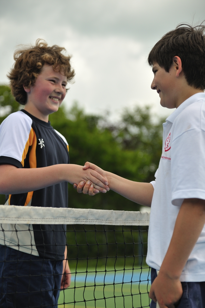 Students shaking hands across a sports net